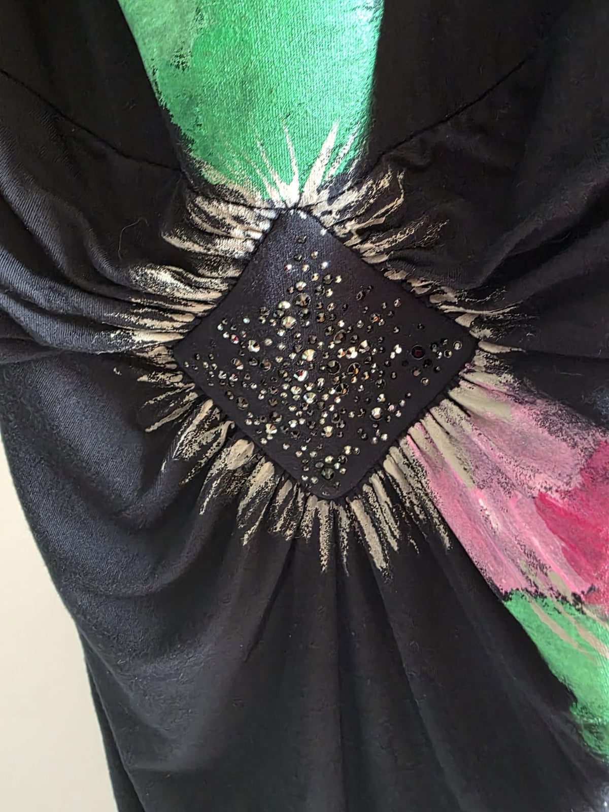 Detalle del fruncido con cristales y la pintura verde y magenta continuando hacia el lateral