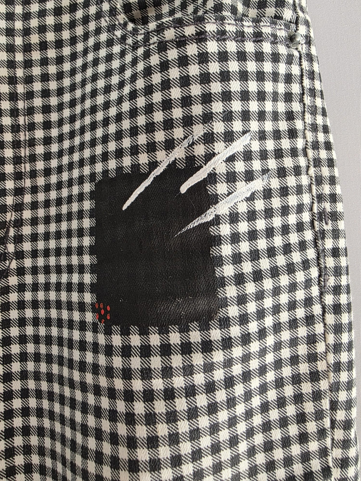 Detalle de pintura negra y trazos blancos sobre el tejido de cuadros blancos y negros