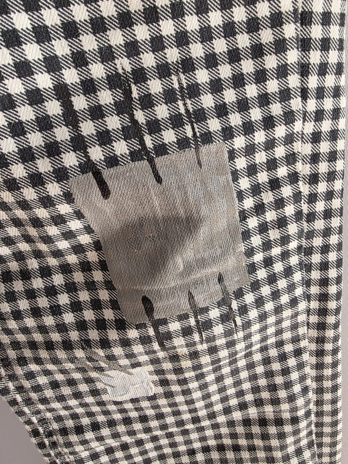 Detalle de la intervención artística pintada a mano sobre el bolsillo del pantalón de cuadros