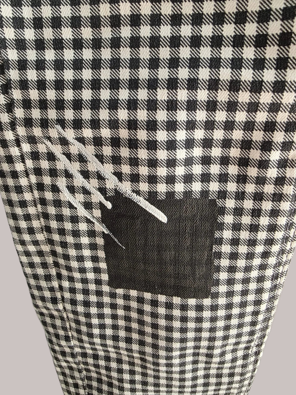 Detalle de pintura blanca y gris aplicada a mano sobre el pantalón de cuadros