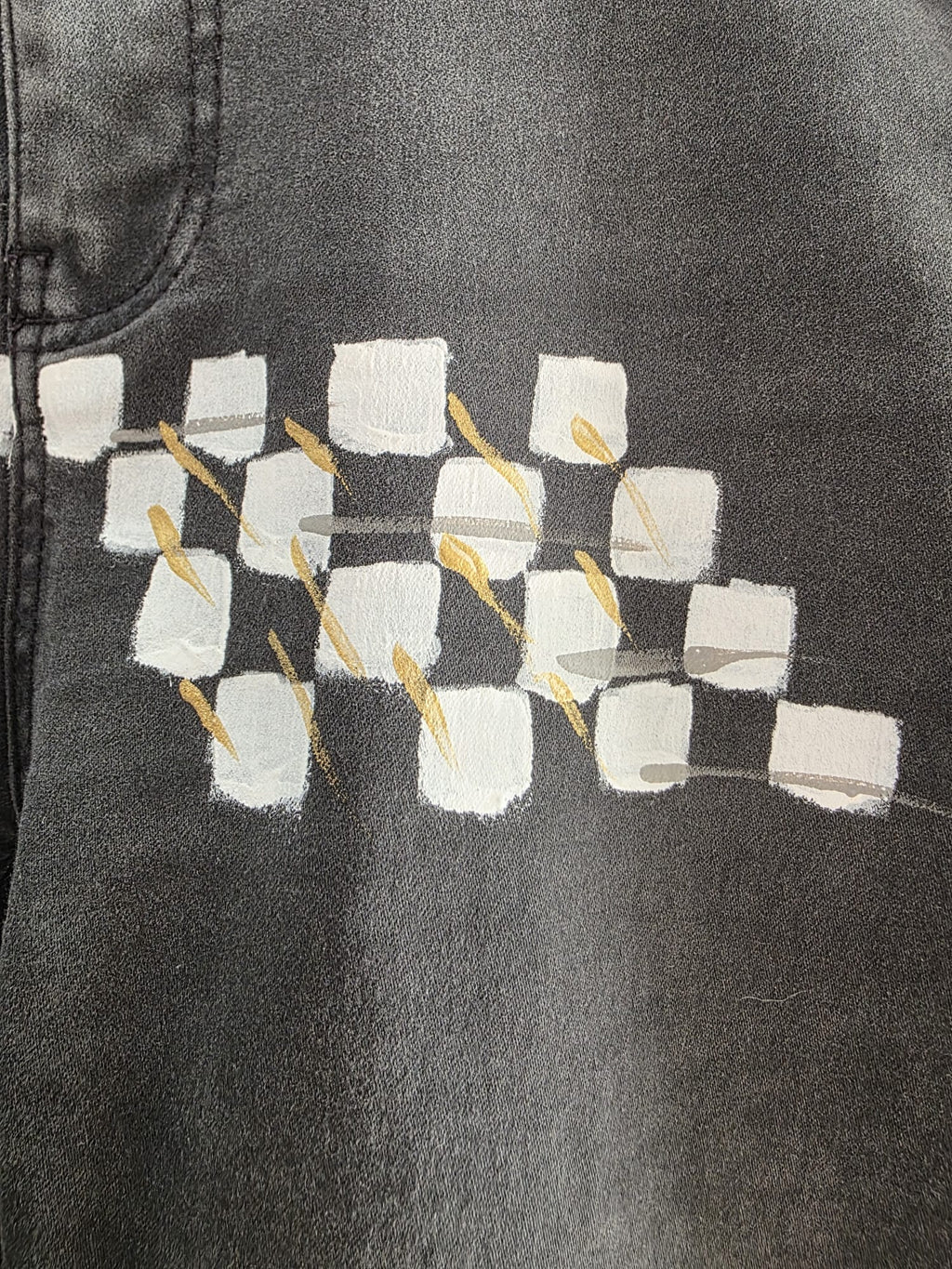 Detalle de cuadrados blancos y grises con trazos amarillos sobre el pantalón