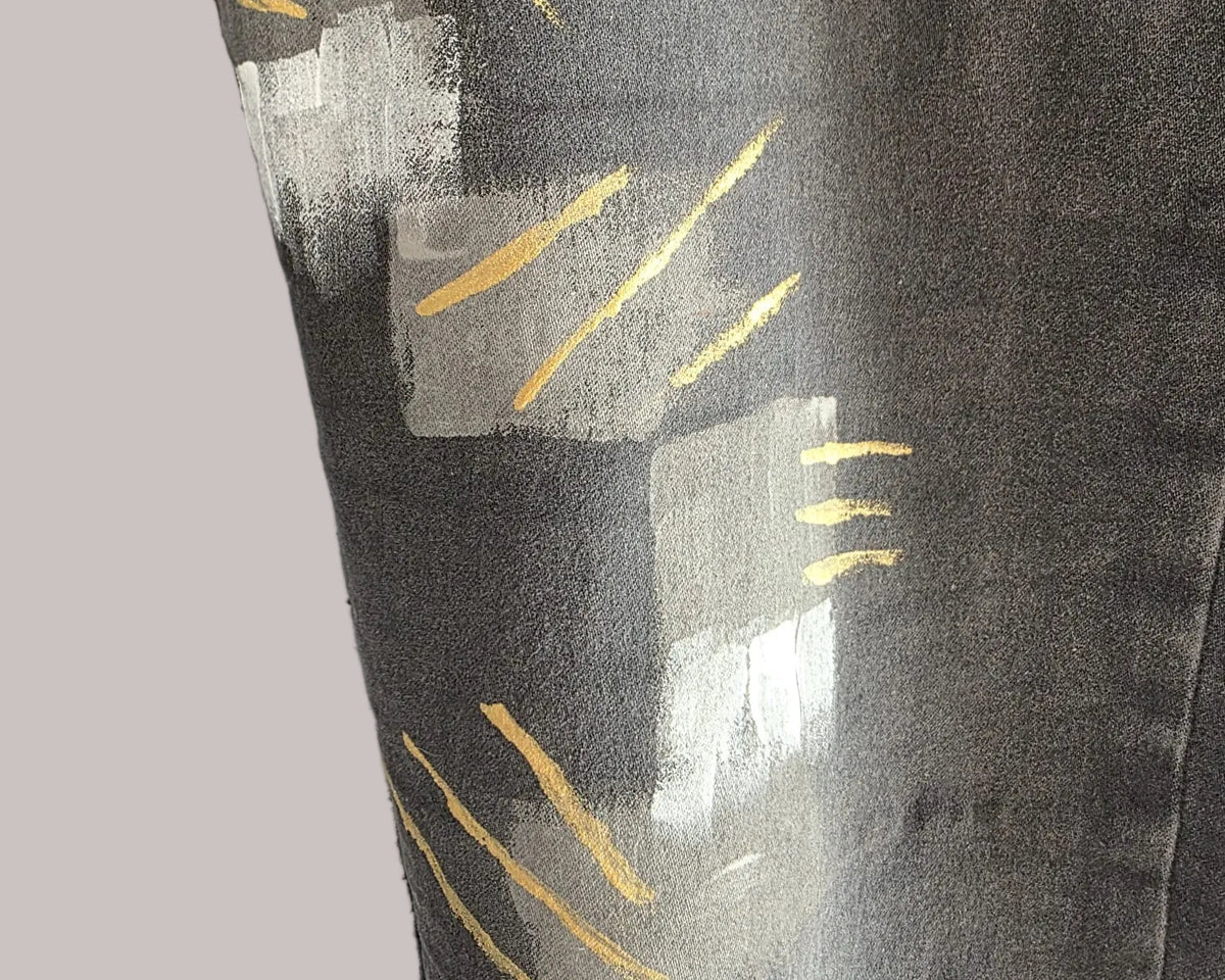 Detalle de formas grises y trazos amarillos pintados sobre el denim gris oscuro