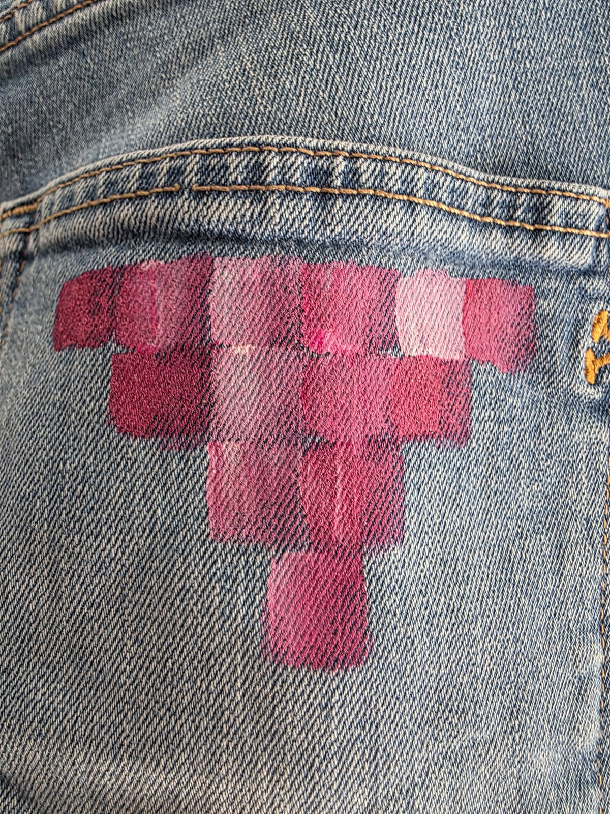 Detalle de bloques geométricos coral y rosa pintados sobre el denim azul