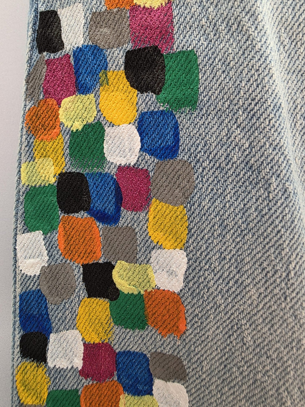 Detalle de la banda geométrica multicolor pintada a mano en el lateral del vaquero