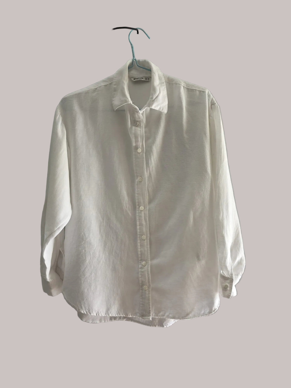 Vista completa de una blusa blanca Stradivarius de manga larga con botones frontales