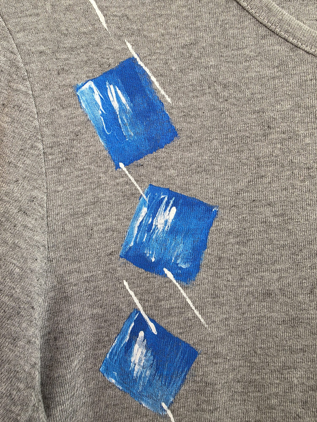 Camiseta gris de manga larga con diseño geométrico azul y blanco, vista frontal