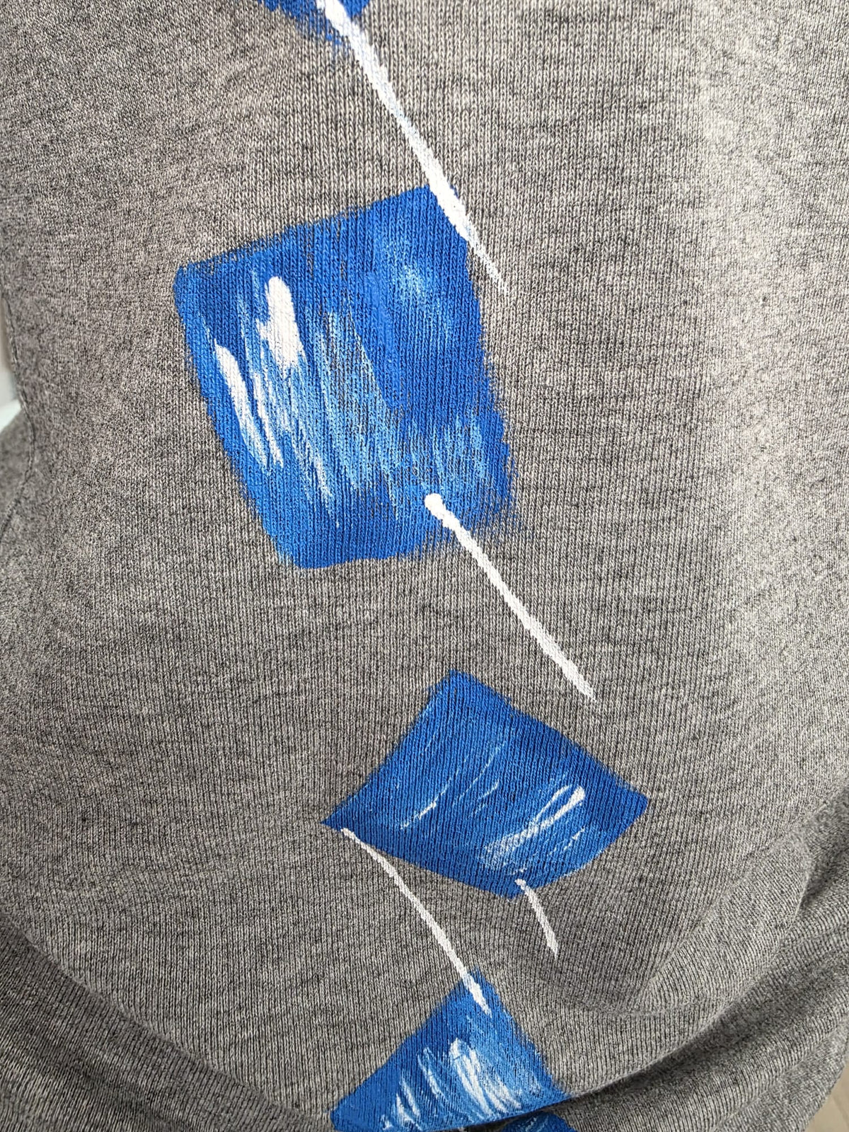 Primer plano del diseño geométrico azul en camiseta gris