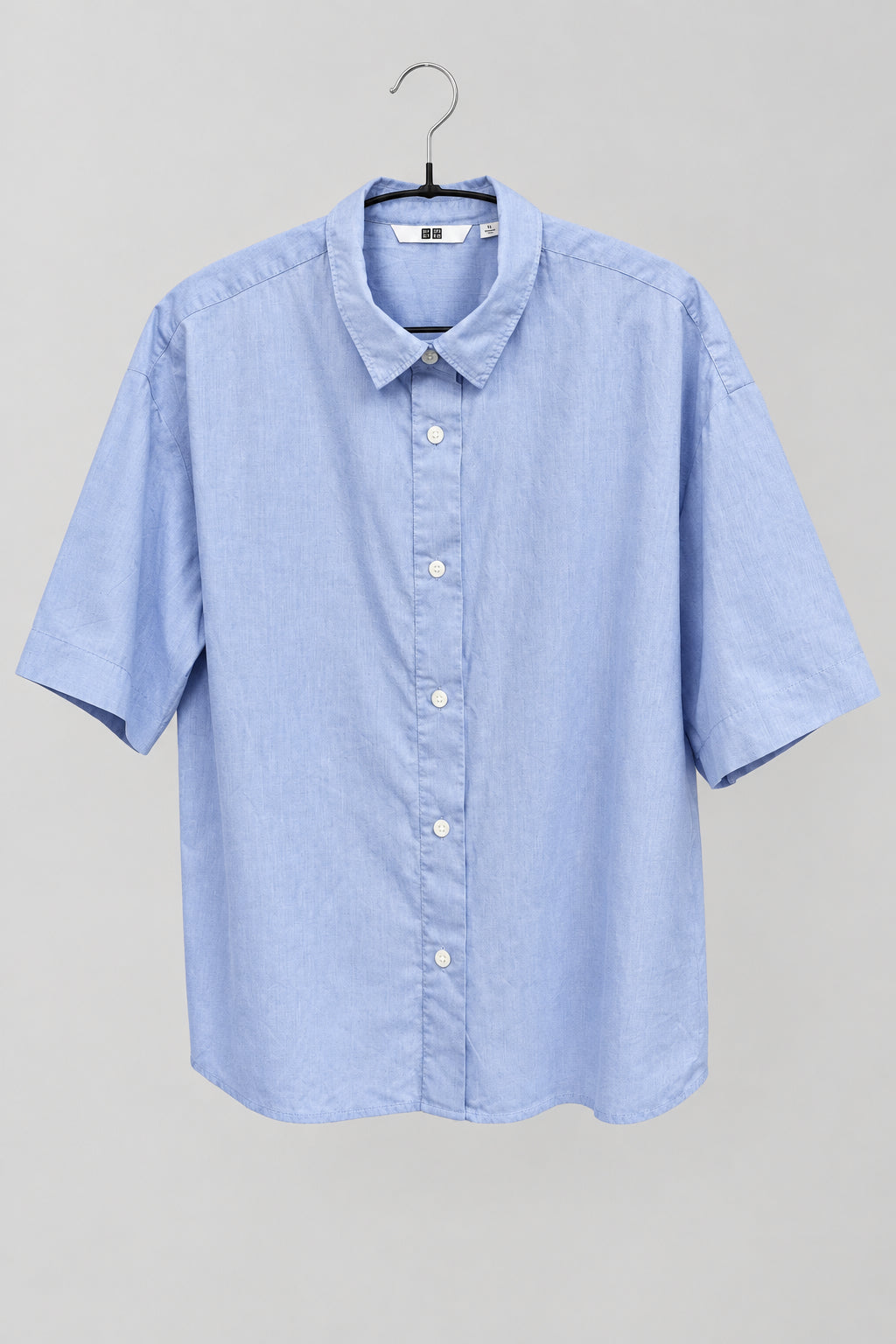 Blusa Uniqlo azul lisa de manga corta colgada, vista frontal
